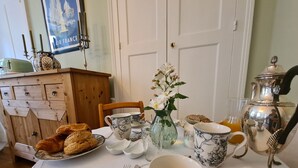 A dining table set with plates, cups, and a vase of flowers. - Cozy Room "Toscane" with Private Bath, 1st Floor, Breakfast Included, Central Châteauroux (Châteauroux)