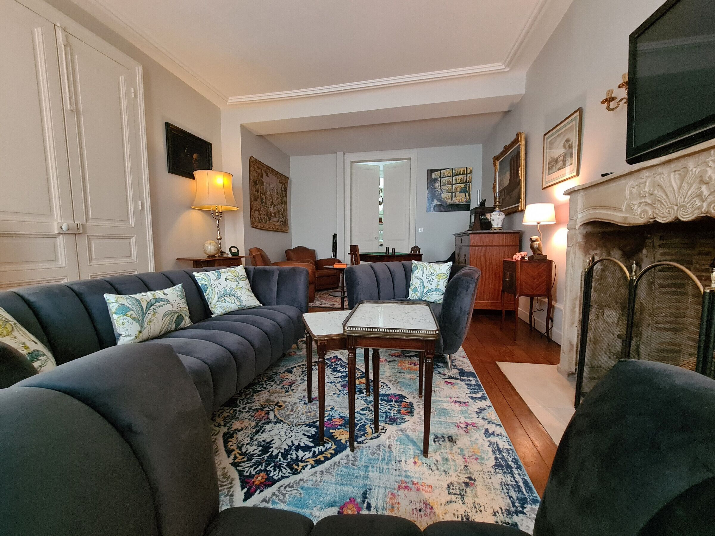 Een woonkamer met een zithoek, een salontafel en een open haard.