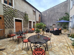 An outdoor patio with stone flooring, metal tables and chairs, and potted plants. - Spacieuse Chambre avec Lit King-Size, Salle d'Eau Privative et Petit-Déjeuner Inclus (Châteauroux)