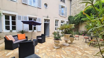 An outdoor patio with wicker furniture, stone flooring, and potted plants.
