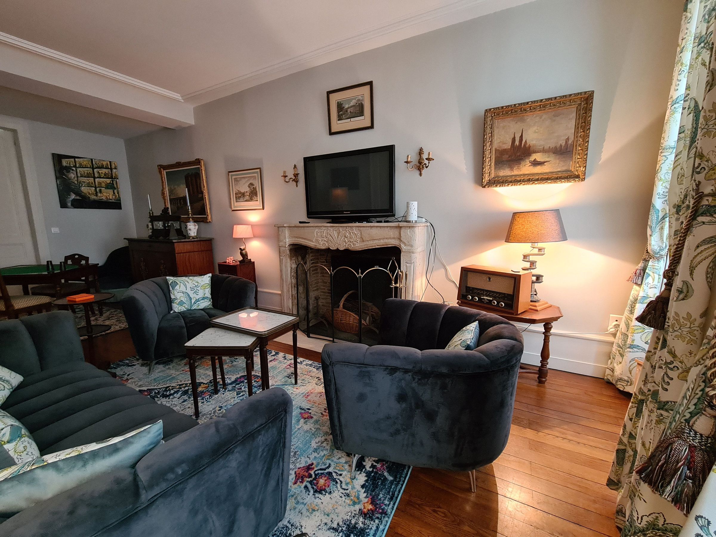 Een woonkamer met een open haard, een televisie en een tafel met stoelen.