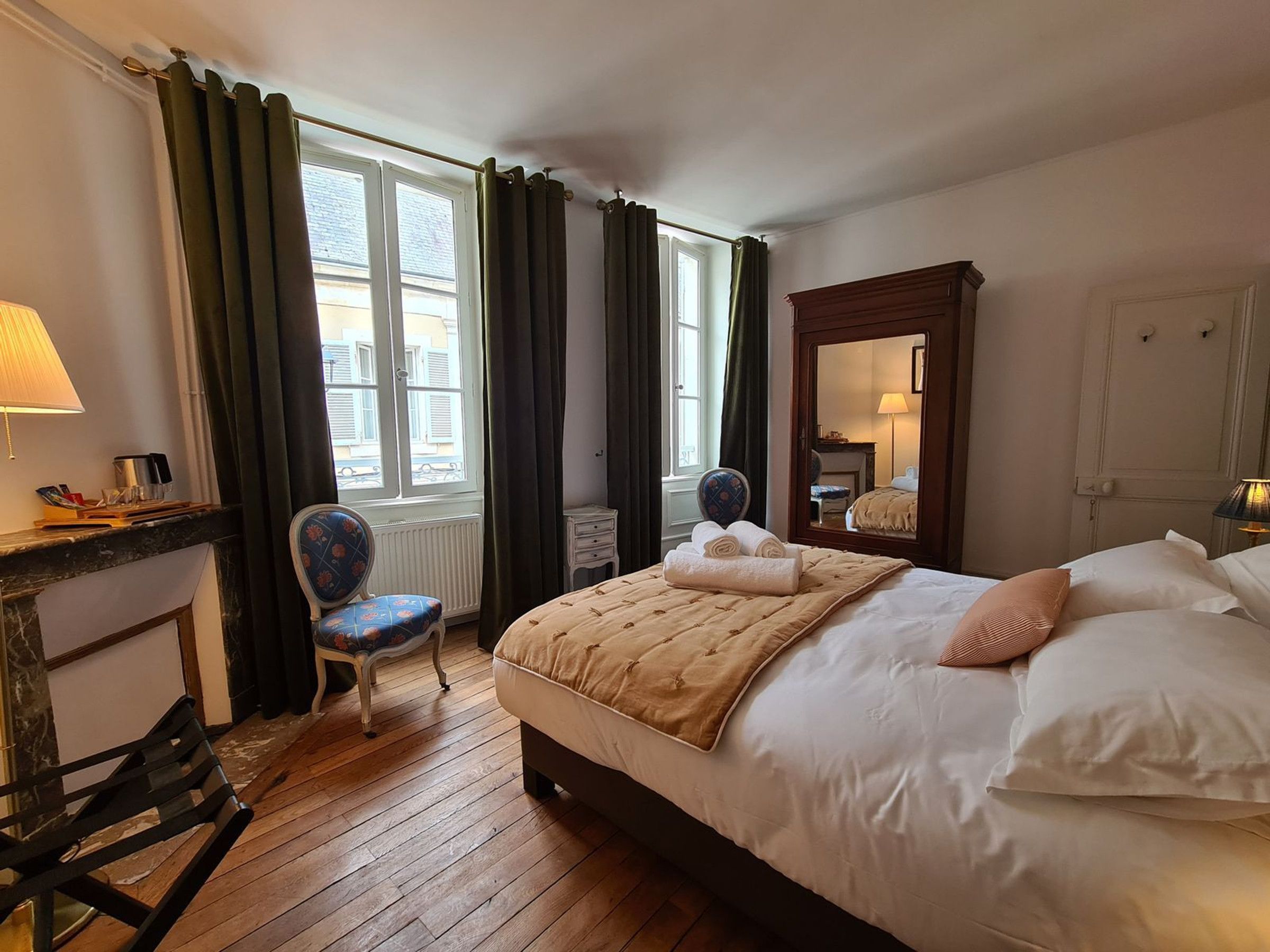 Ein Hotelzimmer mit Bett, Stuhl, Schreibtisch und einem fensterbepflanzten Fenster.