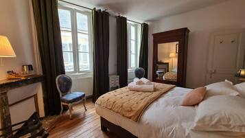 Ein Hotelzimmer mit Bett, Stuhl, Schreibtisch und einem fensterbepflanzten Fenster.