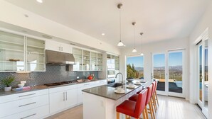 Una cocina moderna con una isla grande, armarios blancos y vistas al exterior.
