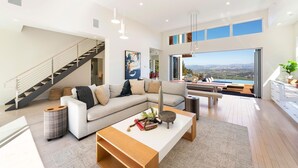 Una sala moderna con sofá, mesa de centro y vista a una piscina y paisaje.