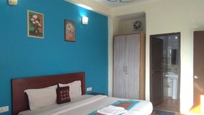 A bedroom with a bed, a wardrobe, and a bathroom visible through an open door. - Corporate Stay (Gurugram)
