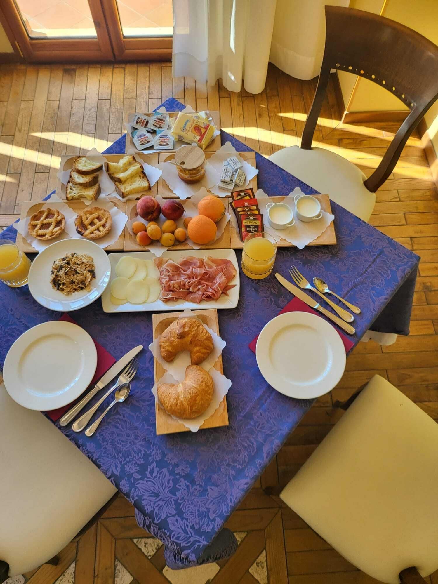 Una tavola imbandita per la colazione con diversi cibi, tra cui pasticcini, frutta e bevande.