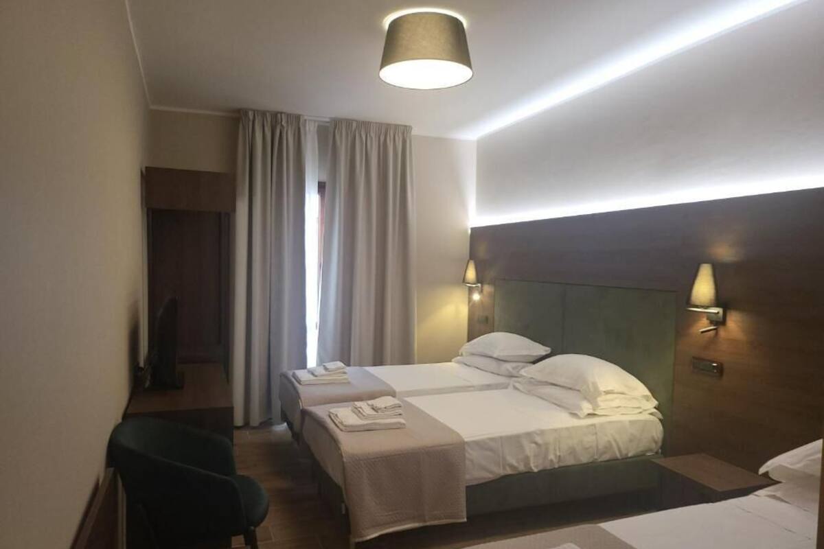 A hotel room with two beds, a desk, and a chair.