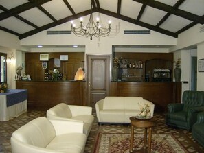 A spacious lobby with a high ceiling, a chandelier, a reception desk, a bar area, and seating arrangements. - La Locanda di Castromediano (Castelmezzano)