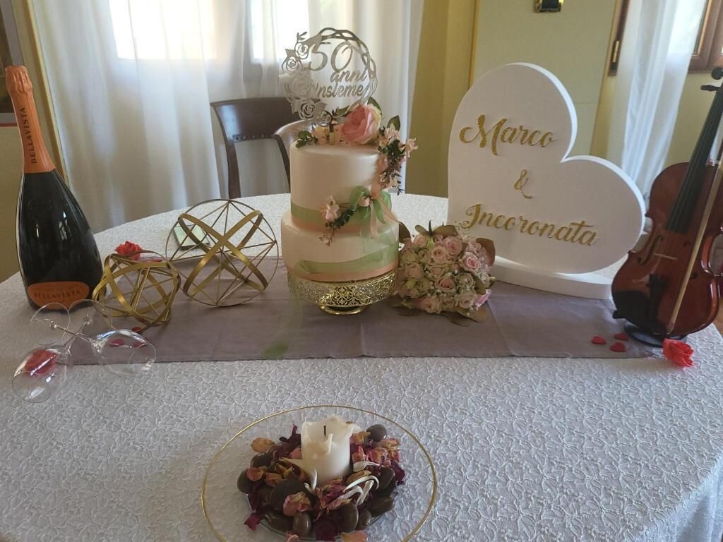A table with a cake, a bottle of wine, glasses, and a violin.