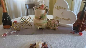A table with a cake, a bottle of wine, glasses, and a violin.