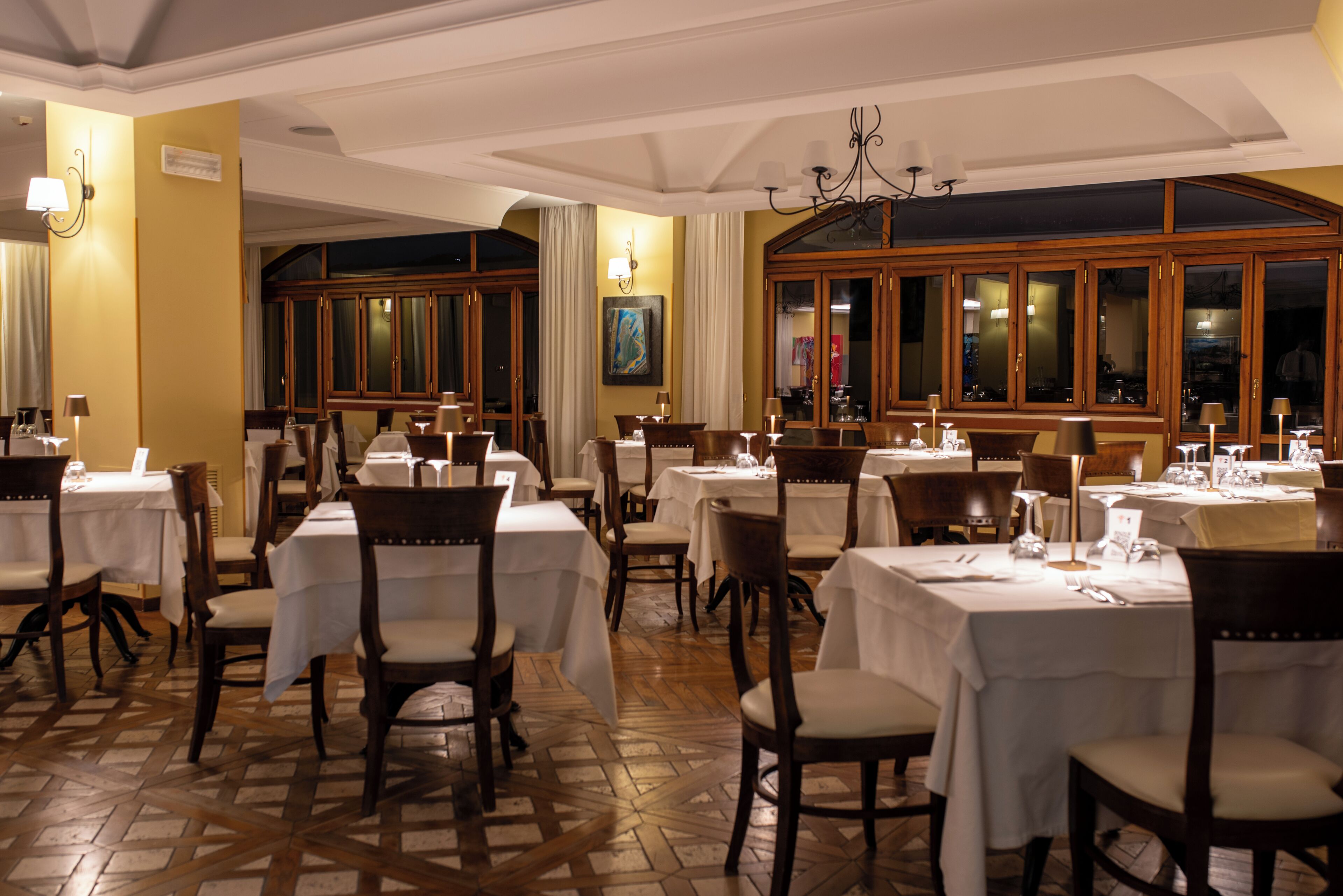 Een restaurant met meerdere tafels en stoelen, houten kasten en een vloer met patroon.