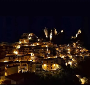 A densely packed hillside village at night with illuminated buildings. - La Locanda di Castromediano (Castelmezzano)