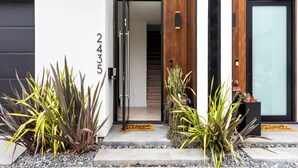 Una entrada moderna a un edificio con puerta de madera, puerta de garaje negra y el número 2435 en la pared.