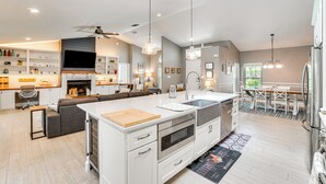 A modern kitchen with a central island, built-in oven, and a dining area with a table and chairs. - Screened Lanai + Fenced Yard: Luxe Orlando Home (Orlando)