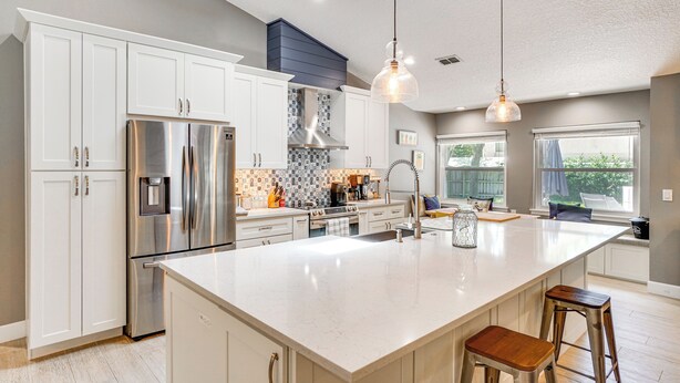 A modern kitchen with white cabinets, stainless steel appliances, and a large island. - Screened Lanai + Fenced Yard: Luxe Orlando Home (Orlando)