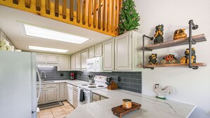Een keuken met witte kasten, een wit fornuis en een houten aanrecht.