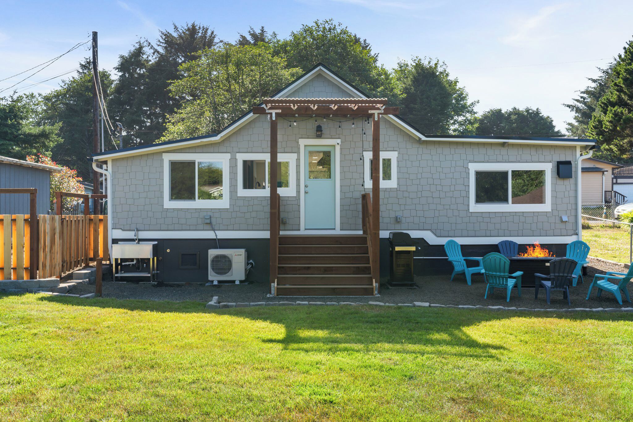 A small, single-story house with a front porch, a fire pit, and outdoor seating.