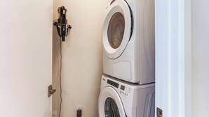 A laundry area with two stacked washing machines and a wall-mounted dryer. - Ocean Views & Pool Access: Riviera Beach Condo! (Singer Island)