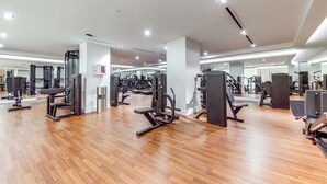 A gym with various exercise machines, wooden flooring, and mirrors on the walls. - Ocean Views & Pool Access: Riviera Beach Condo! (Singer Island)