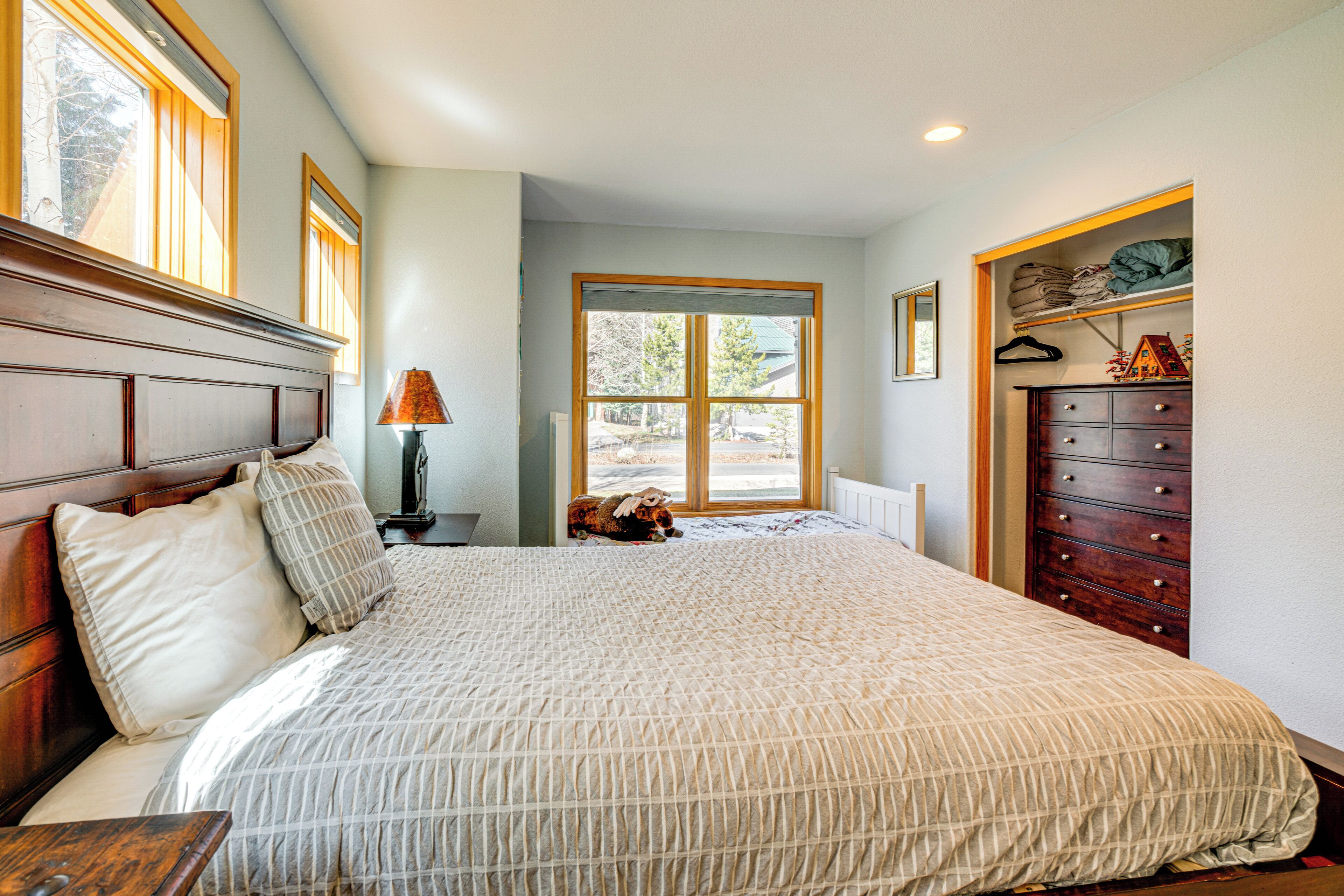 A bedroom with a large bed, wooden headboard, a dresser, and a window with a view of the outdoors.