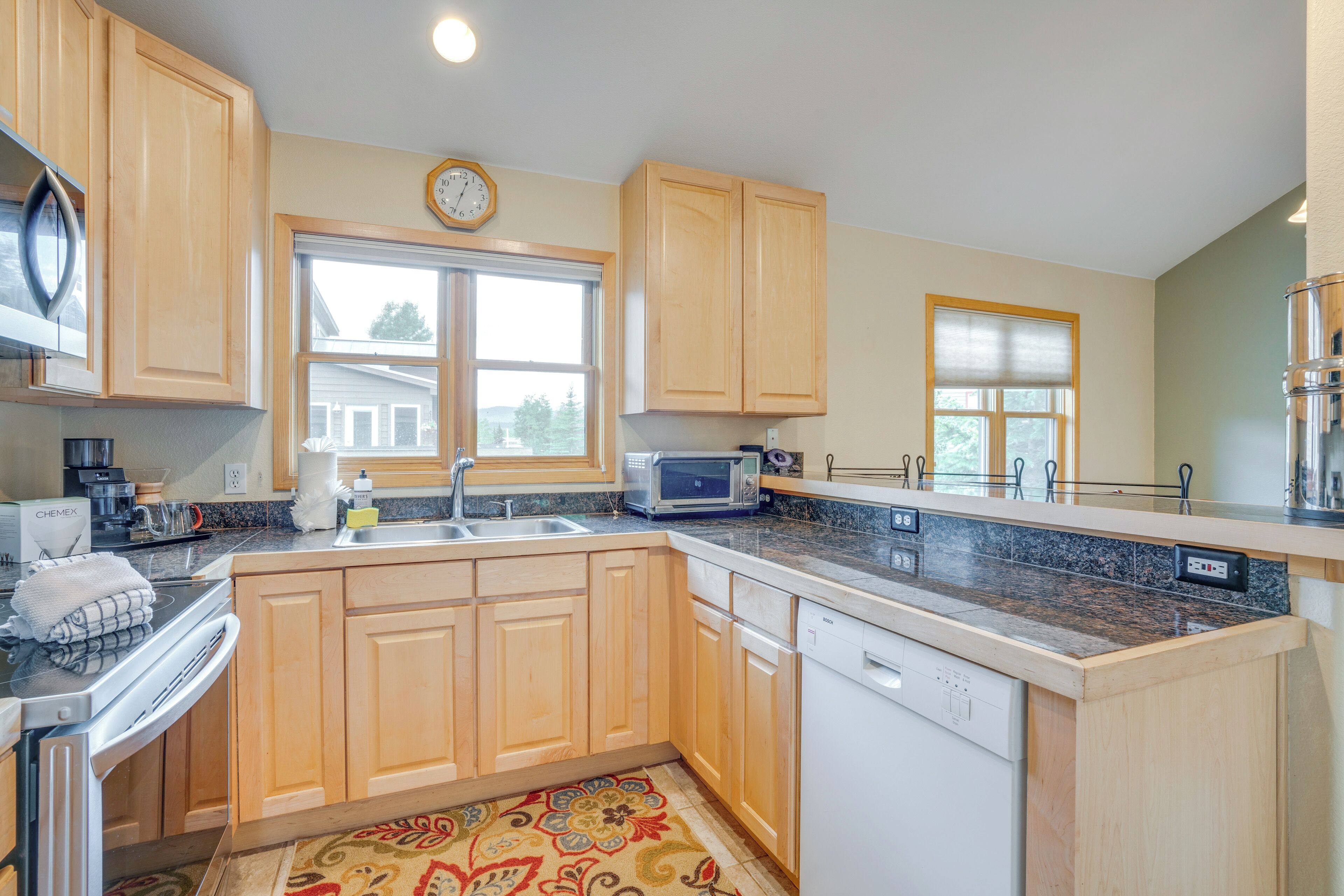 A kitchen with wooden cabinets, a microwave, a sink, and a dishwasher.