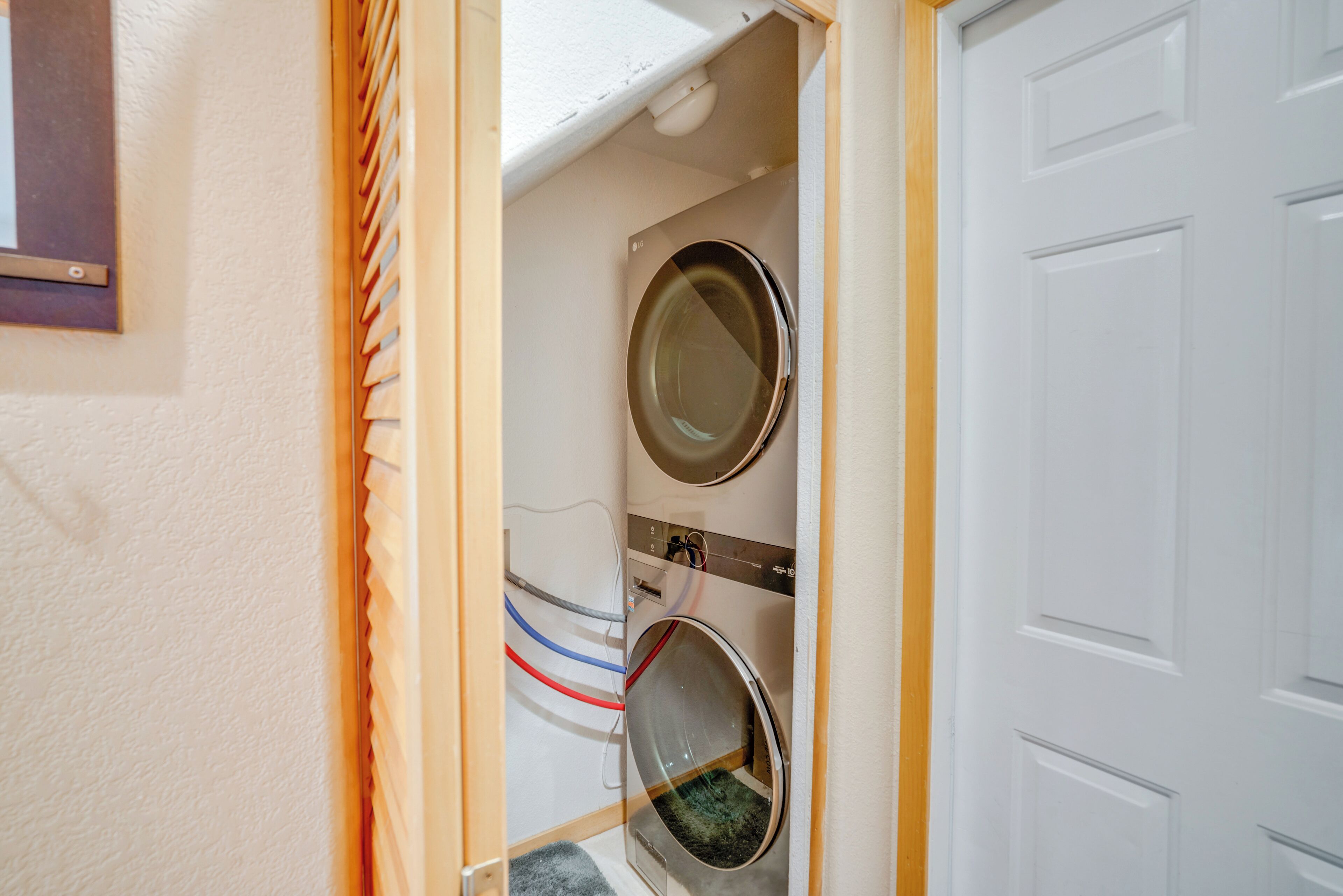 A laundry room with two washing machines, a door, and a small window.
