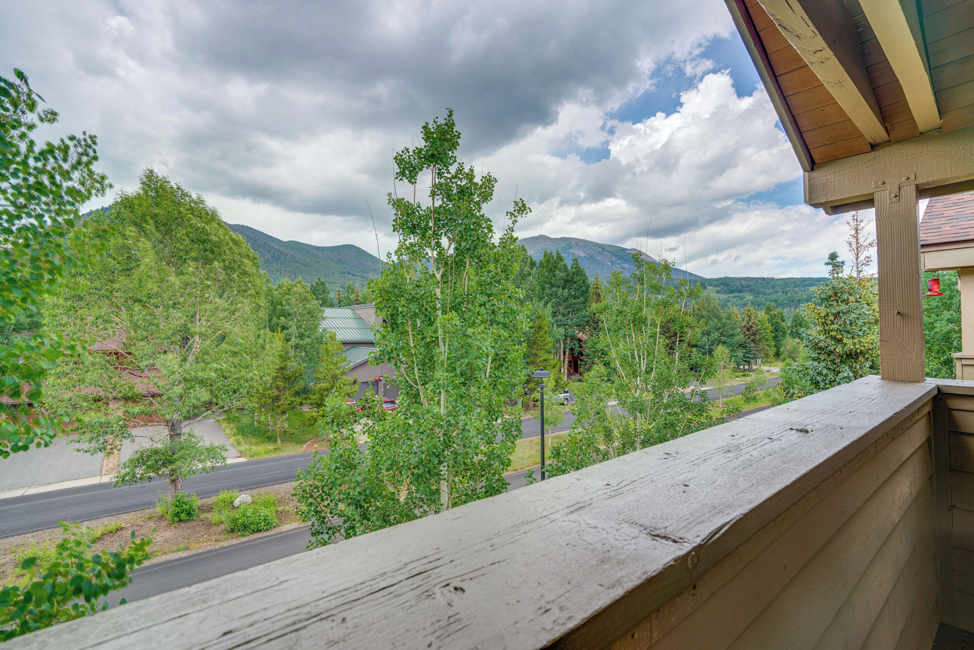 A balcony with a view of a road, trees, and mountains.