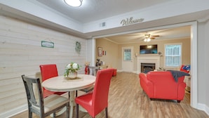 A dining area with a round table and red chairs, a red sofa, and a fireplace in the background. - Quaint Augusta Townhome: 3 Mi to the Masters! (Augusta)