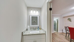 A bathroom with a granite countertop sink, white cabinets, and a mirror with three lights. - Quaint Augusta Townhome: 3 Mi to the Masters! (Augusta)