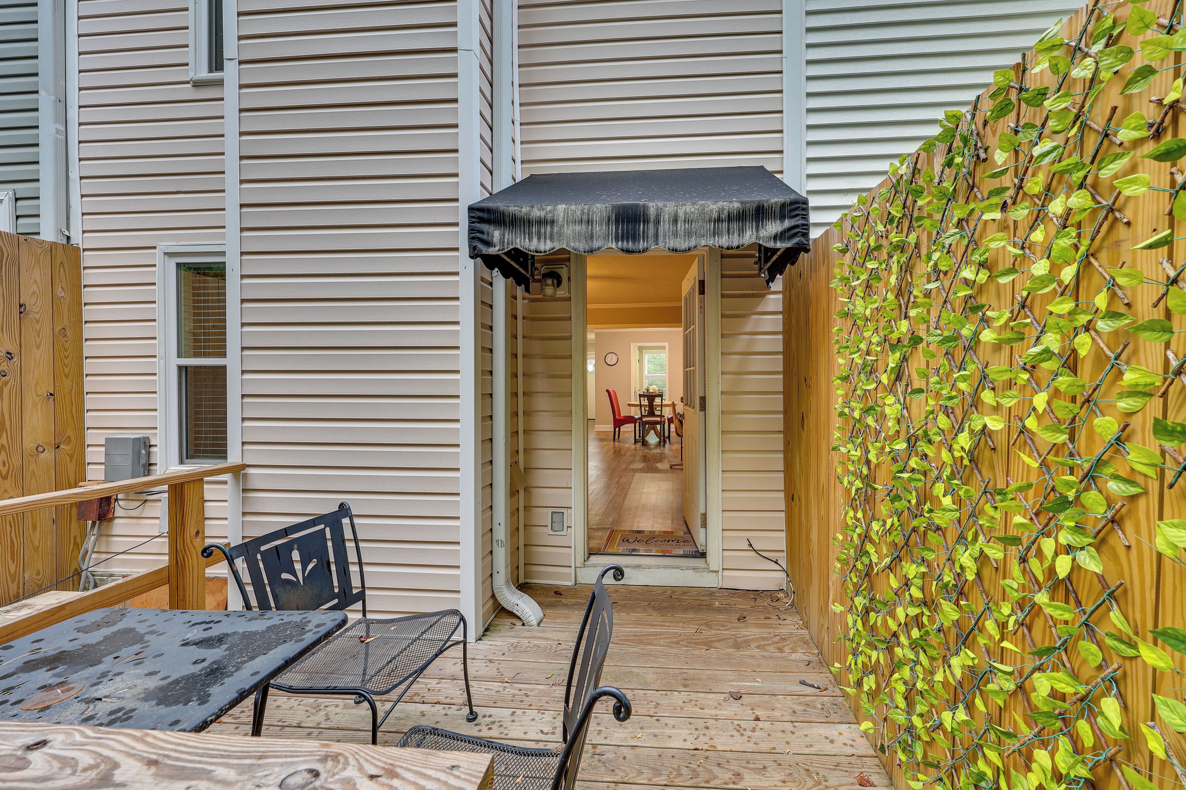 A covered patio area with a wooden fence, a table, and chairs.