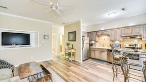 A modern kitchen with wooden cabinets, stainless steel appliances, and a dining area with metal chairs. - Huntsville Condo w/ Patio Near Redstone Arsenal! (Huntsville)