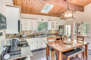 Una cocina con armarios blancos, una mesa de comedor de madera y una cafetera.