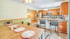 A modern kitchen with wooden cabinets, a central island, and a dining area with a wooden table and chairs. - Game Room & Private Yard: Family Gem in Kunkletown (Kunkletown)