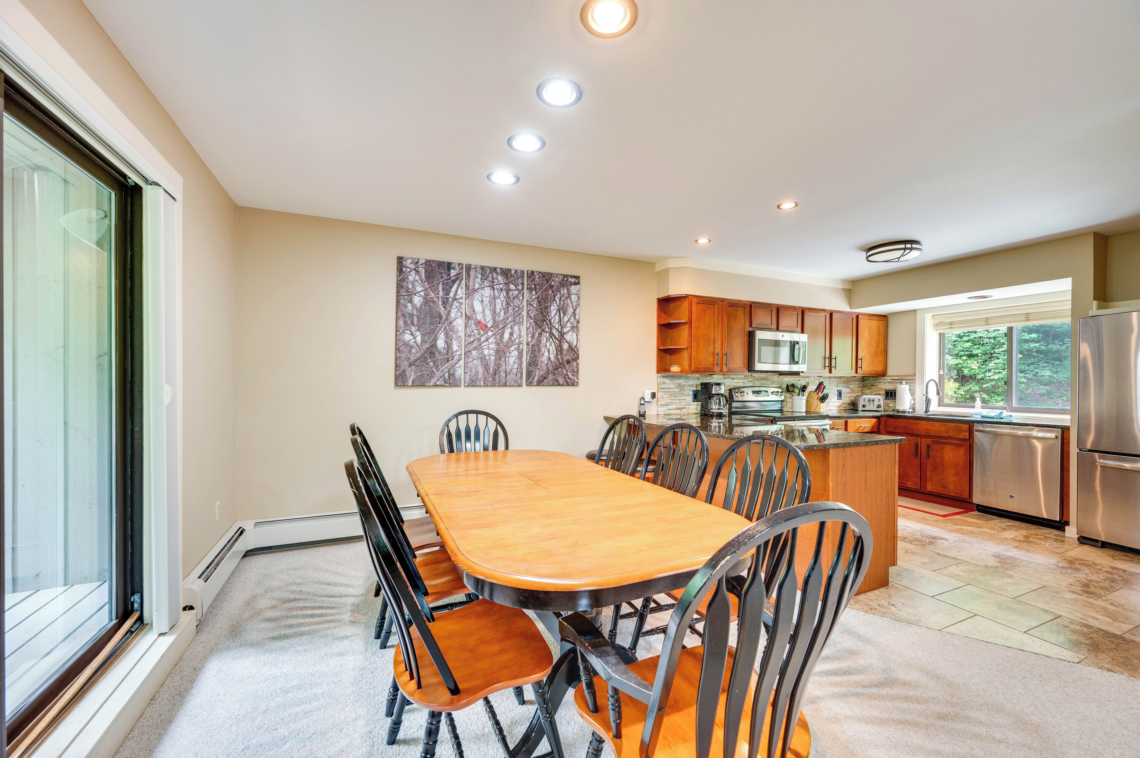 A modern kitchen with a dining area, featuring a large wooden table, chairs, and built-in appliances.