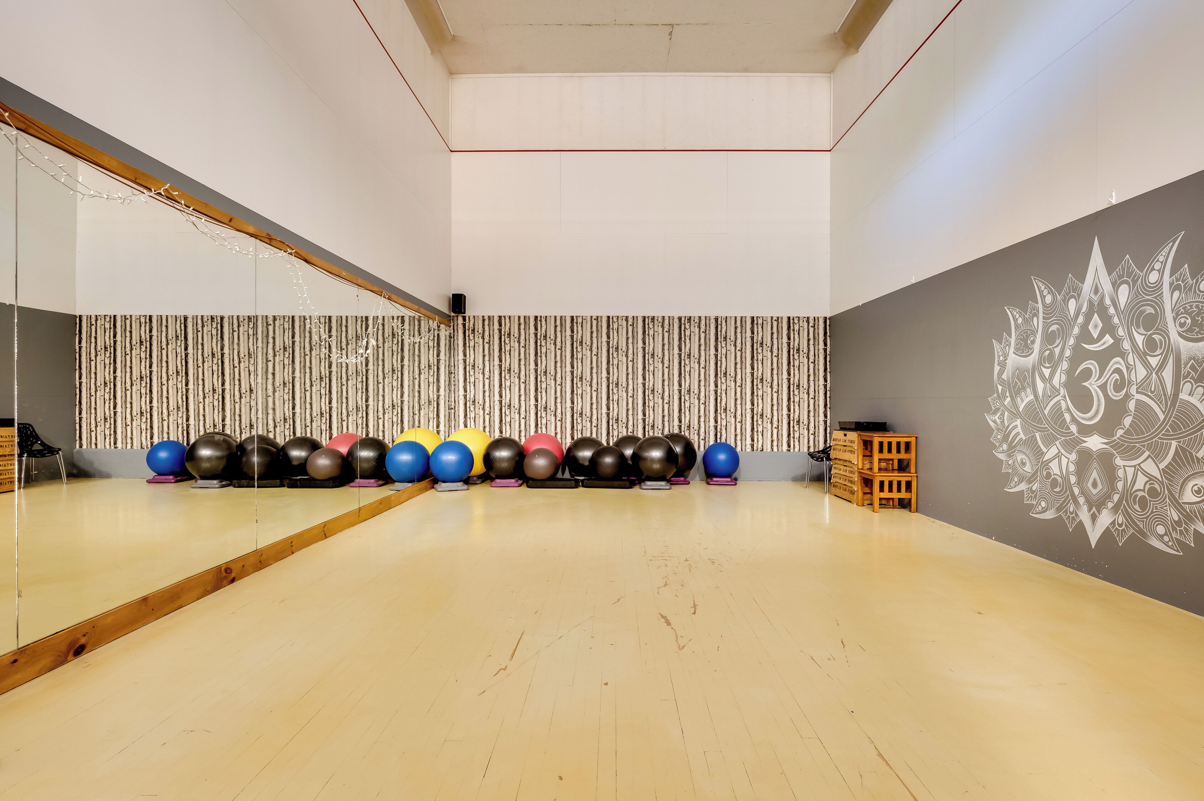 Un gimnasio con pelotas de ejercicio, un espejo y una pared decorativa.