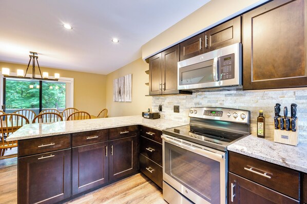 A modern kitchen with dark wood cabinets, stainless steel appliances, and a granite countertop. - Lincoln Townhome w/ Community Pool & Club Access! (Lincoln)