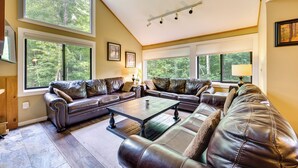 A spacious living room with leather sofas, a coffee table, and large windows offering a view of the outdoors. - Lincoln Townhome w/ Community Pool & Club Access! (Lincoln)