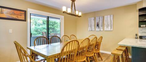 A dining area with a wooden table and chairs, a chandelier, and artwork on the walls.