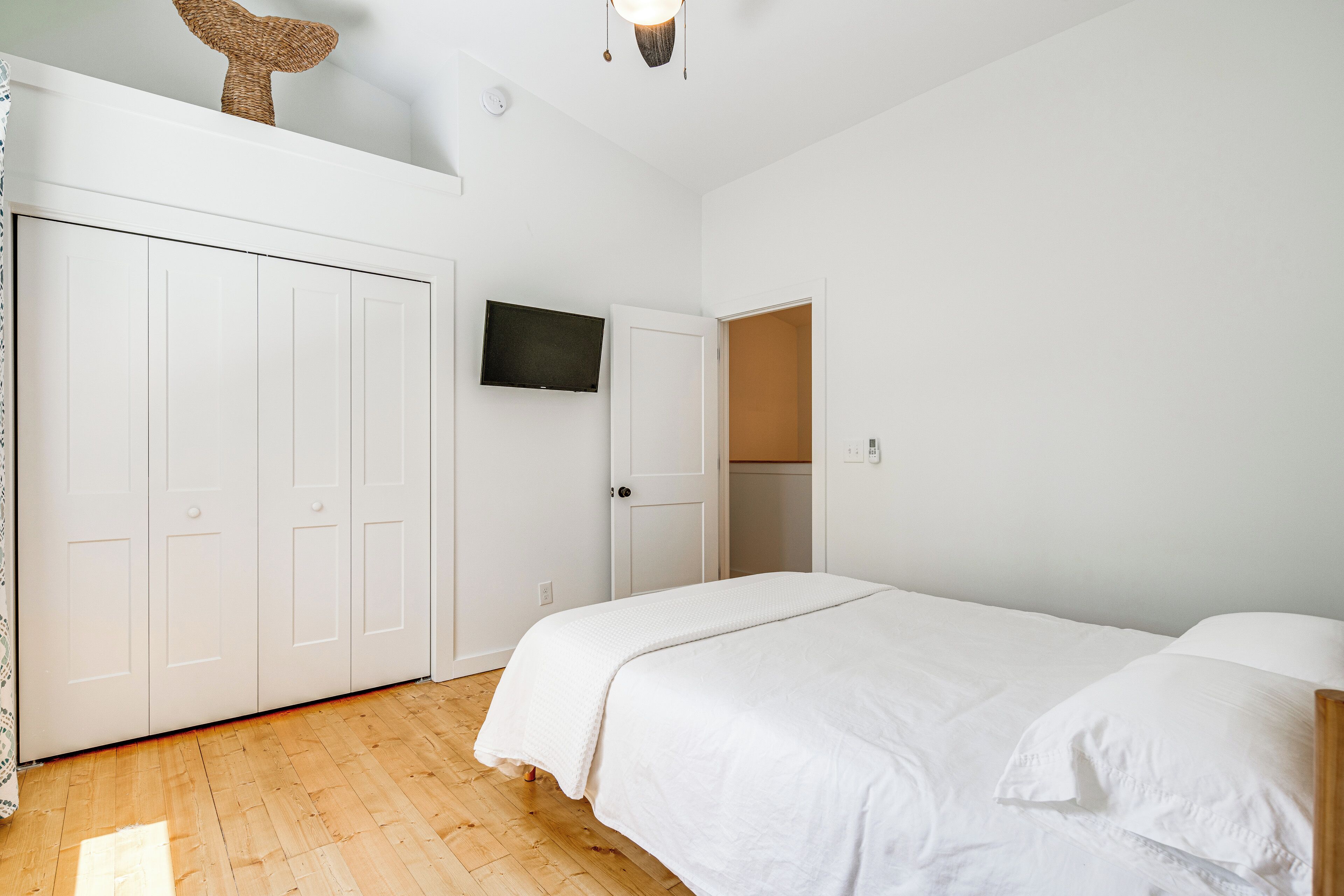 Ein Schlafzimmer mit Bett, Kleiderschrank und Fernseher an der Wand.
