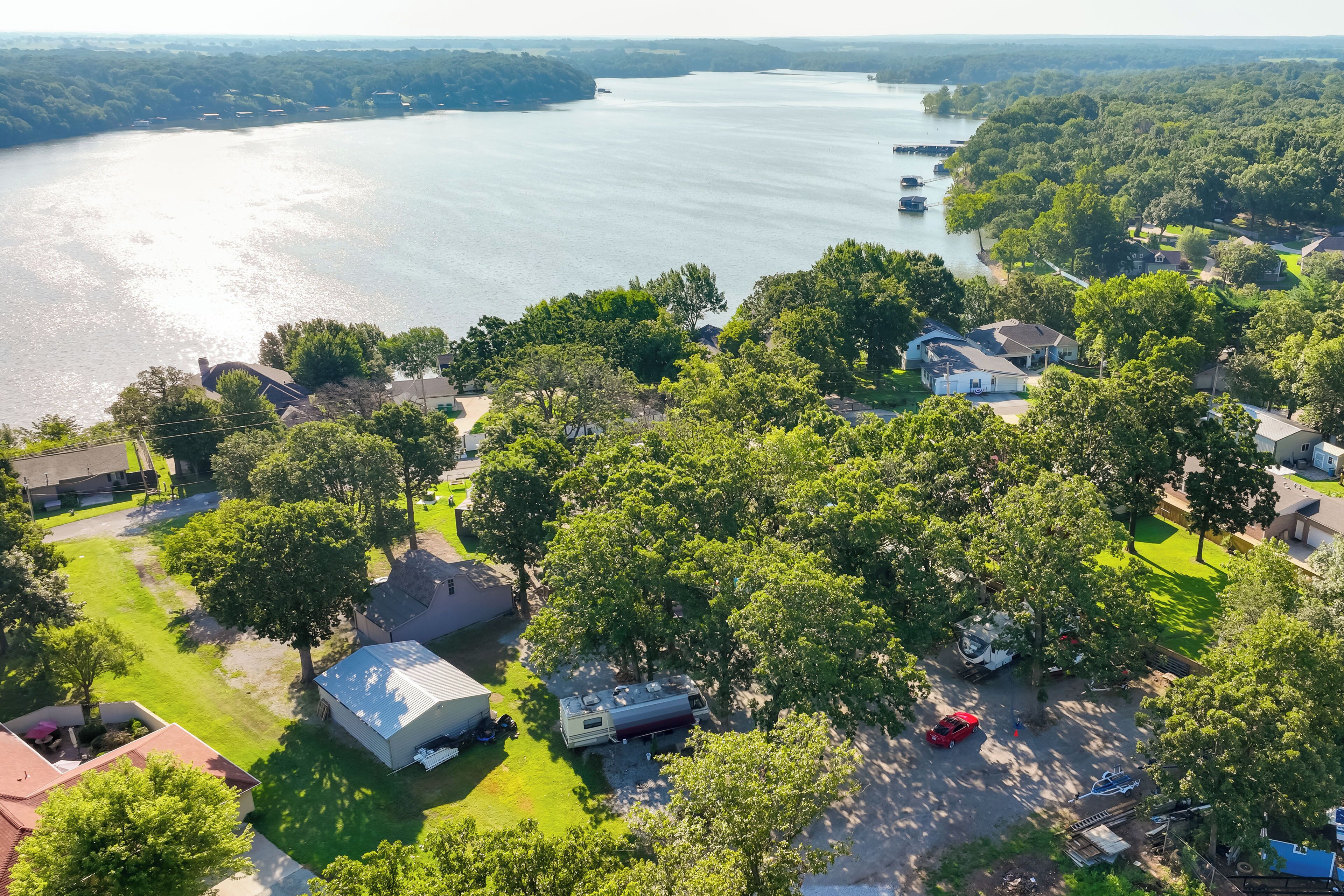 An aerial view of a lakeside residential area with houses, a boat dock, and a large RV.