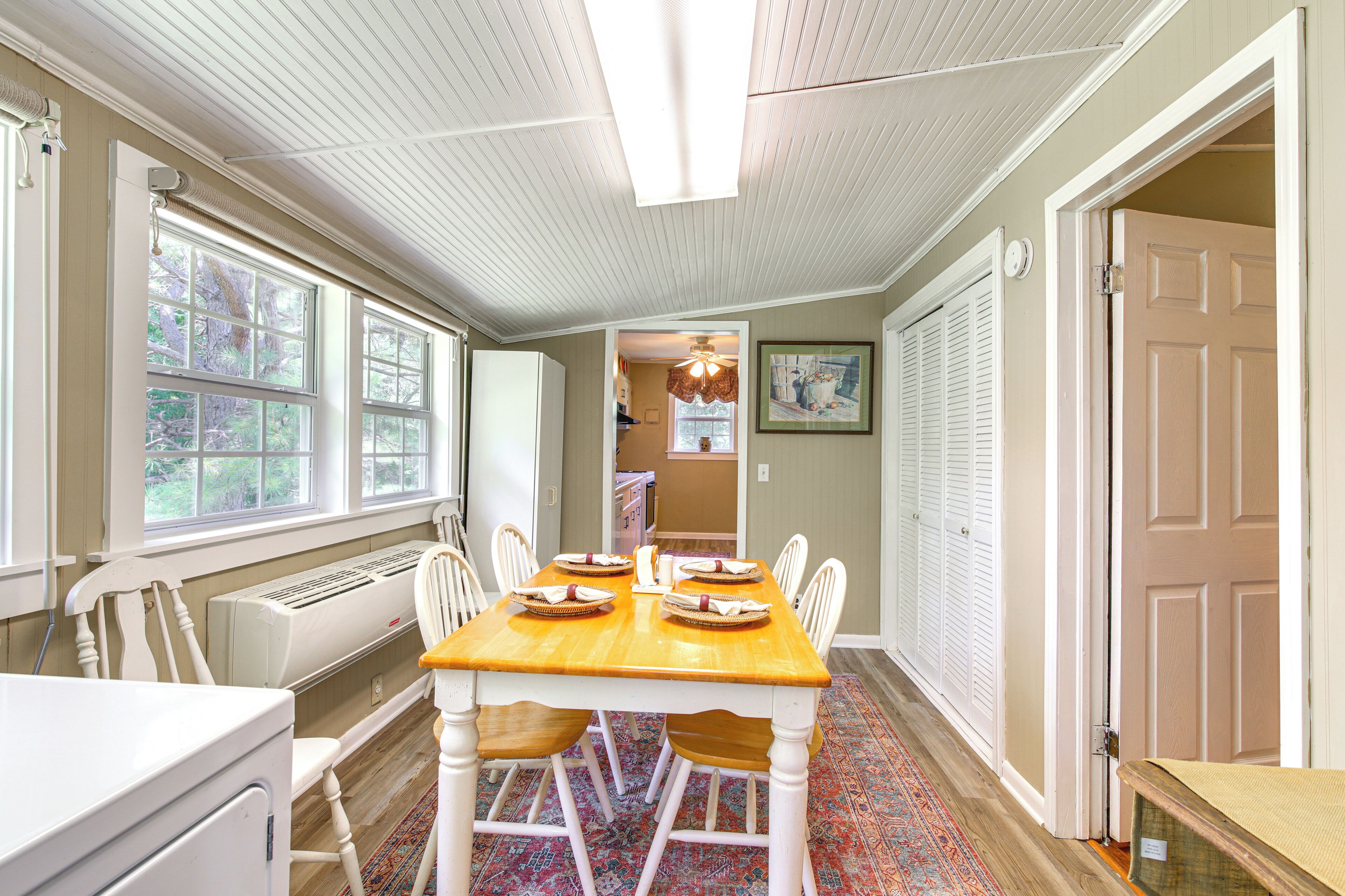 A dining area with a wooden table, white chairs, and a ceiling fan.