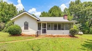 A single-story house with a porch, a chimney, and a well-maintained lawn. - Charming Country Home w/ Yard - 14 Mi to Ole Miss! (Oxford)