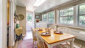 A dining area with a wooden table set for four, white chairs, and a window with a view of trees. - Charming Country Home w/ Yard - 14 Mi to Ole Miss! (Oxford)