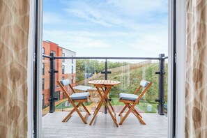 Enjoy a peaceful view from this balcony with a table and chairs, overlooking a beautifully landscaped area.