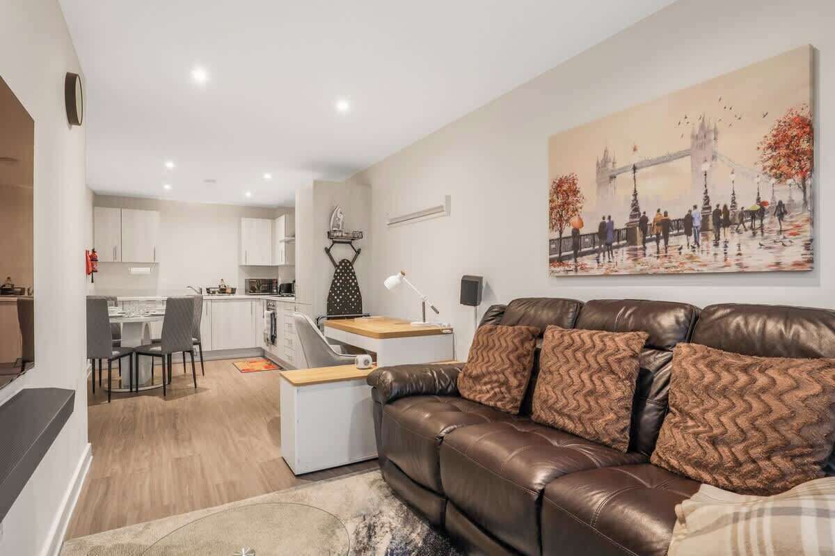 Ein modernes Wohnzimmer mit einer braunen Ledersofa, einem Essbereich mit weißen Schränken und einer Küche im Hintergrund.