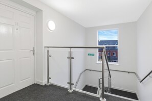 Stairwell with a door to a space and a window offering a view of the surrounding area.