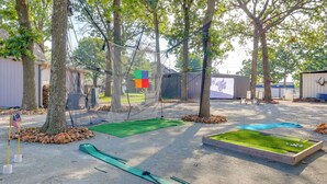 A miniature golf course with sand traps, a green mat, and a netted area. - Pet-friendly Grand Lake Studio w/ Outdoor Space (Grove)
