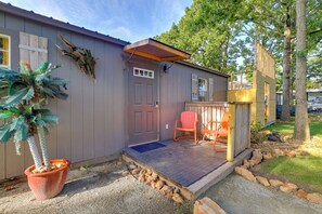 A small wooden structure with a porch, a door, and two chairs. - Pet-friendly Grand Lake Studio w/ Outdoor Space (Grove)