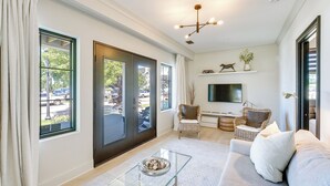 A modern living room with a sofa, a glass coffee table, and a TV.